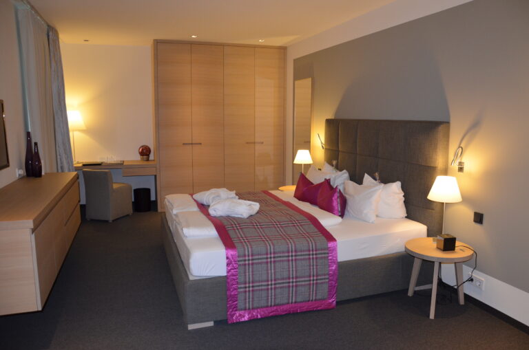 Das große Schlafzimmer mit stimmungsvoller Beleuchtung im Golfhotel Dolomitengolf
