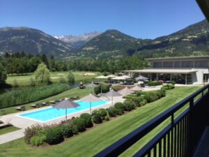Blick vom Balkon des Golfhotels auf Pool, Golfplatz und Berge